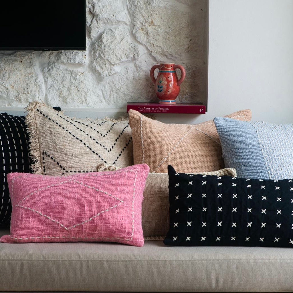 Collection of patterned pillows on a sofa against a stone wall background