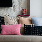 Collection of patterned pillows on a sofa against a stone wall background