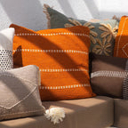 Decorative pillows on a couch with a vase and glass on a table in the foreground.