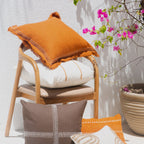 Decorative pillows on a chair with a potted plant and flowers in the background