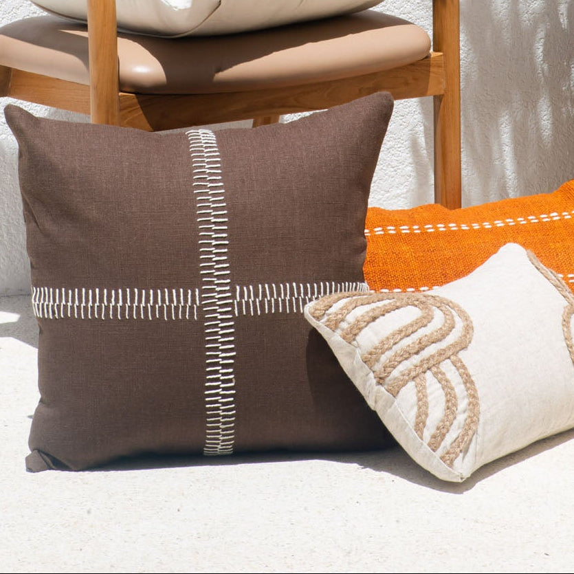 Decorative pillows on a chair with a potted plant and flowers in the background