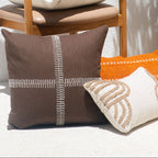 Decorative pillows on a chair with a potted plant and flowers in the background