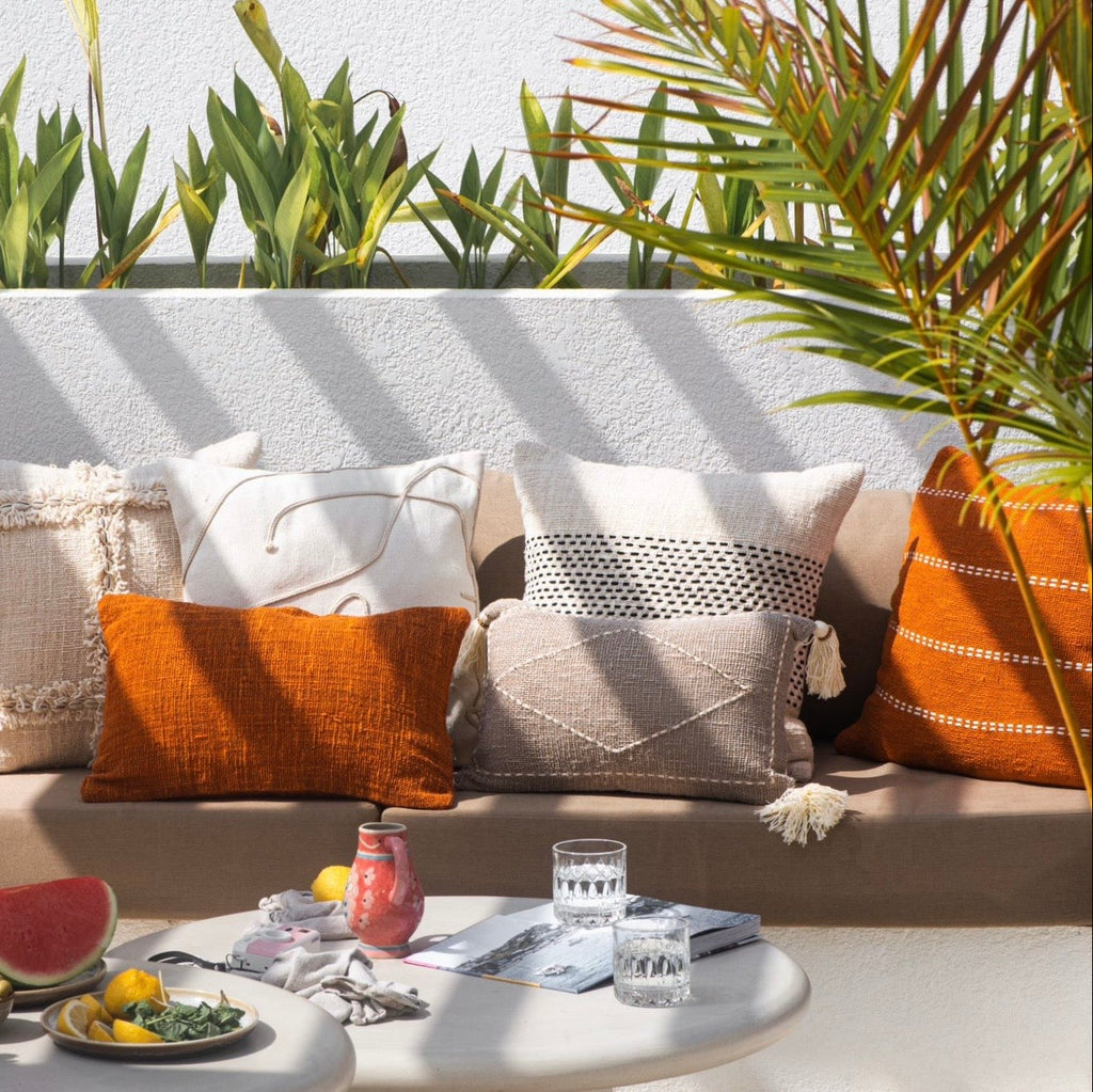 Outdoor seating area with colorful pillows and a small table with snacks and drinks.