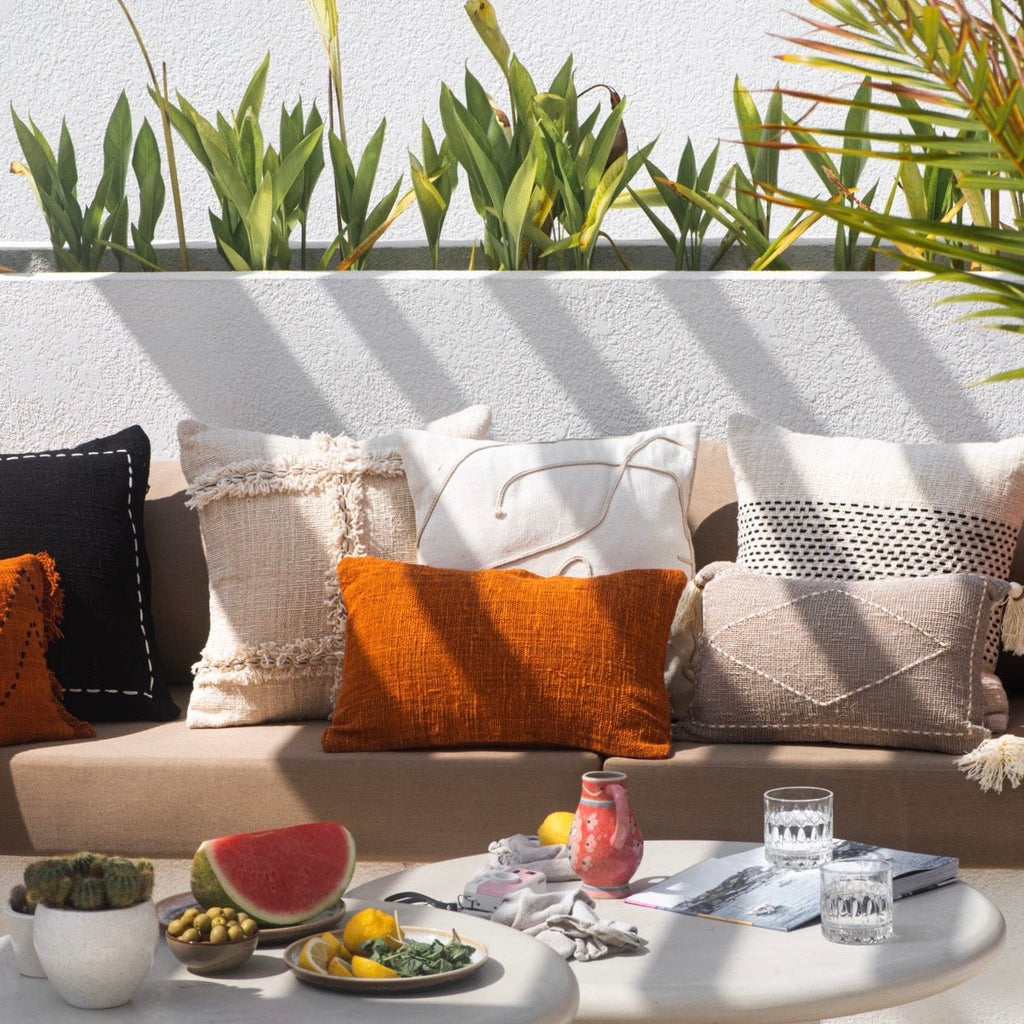 Outdoor seating area with colorful pillows and a small table with snacks and drinks
