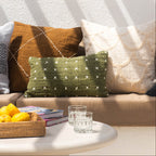 Decorative pillows on a couch with a coffee table and plants in the background