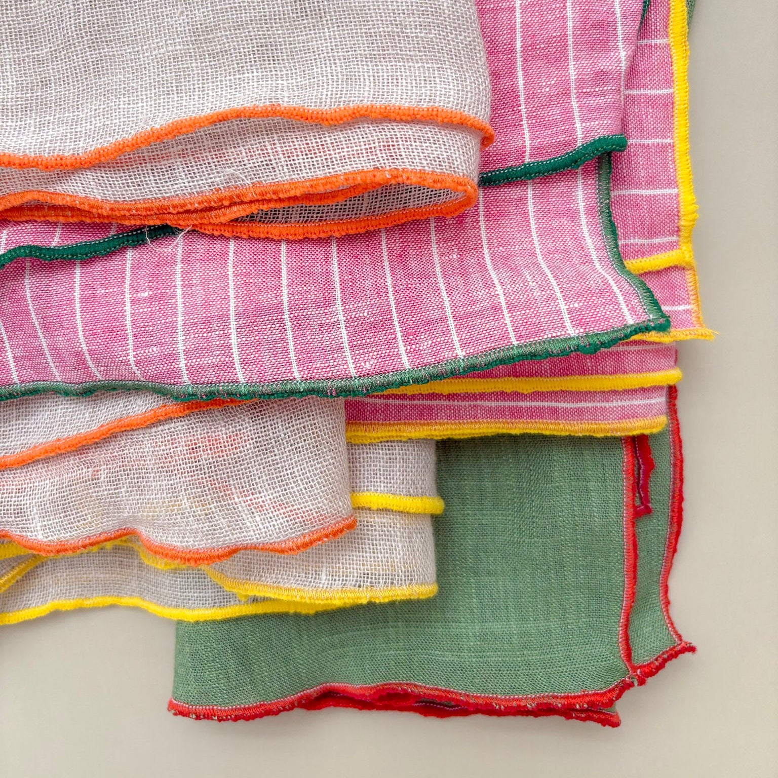 Stack of colorful napkins with multicolored edges on a light background