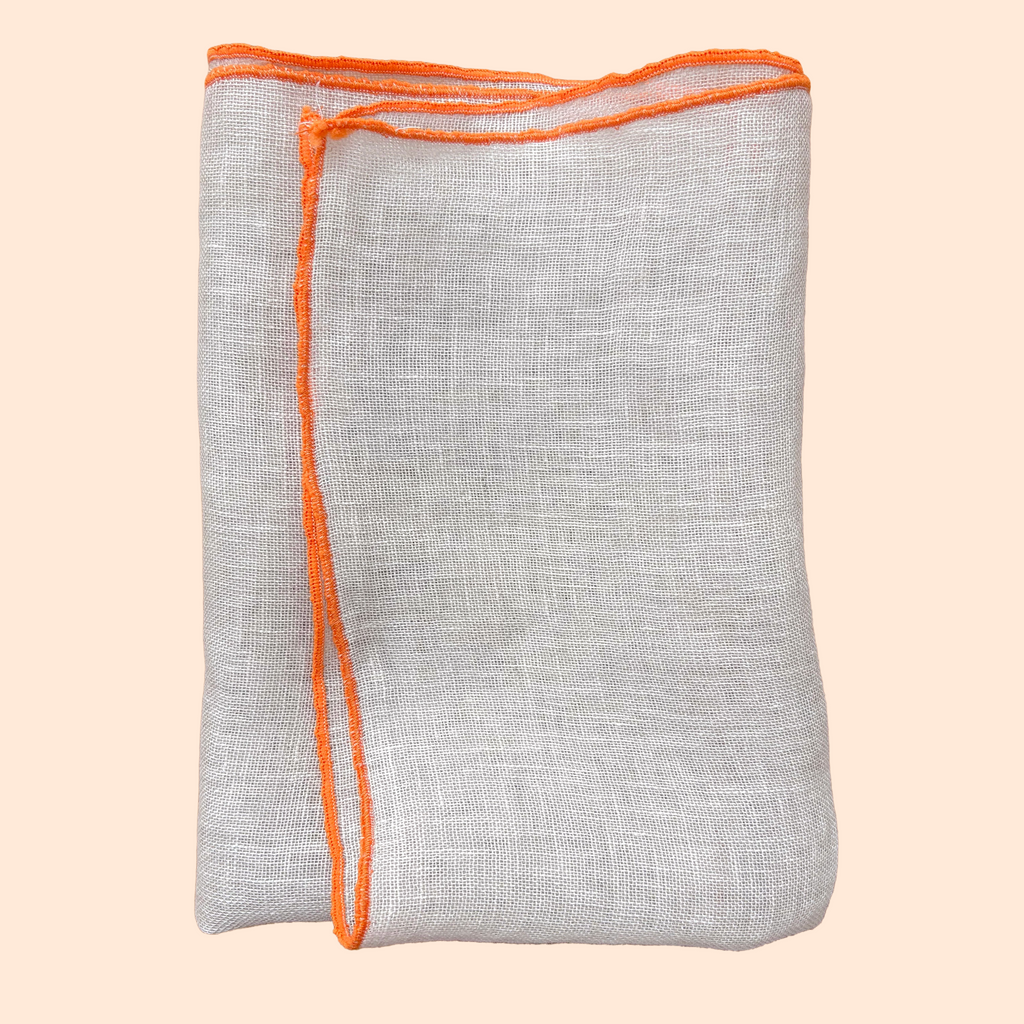 Isolated product image of natural linen napkin with orange hem on soft background