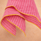 Pink napkin with white stripes and yellow border on a beige background
